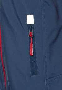 Navy blue fabric with a red-accented zipper pocket. Zipper features a pull tab labeled "TROLLKIDS." Smooth, slightly textured finish.
