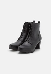 Bottines en cuir noir avec un talon haut, dotées d'un laçage frontal et d'une texture lisse avec des coutures renforcées.
