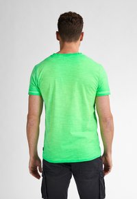 Tricou scurt, verde, cu mânecă scurtă, dintr-un material texturat, melanj, cu guler rotund și margini contrastante la mâneci și guler.