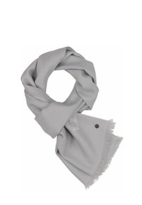 Écharpe gris clair en tissu doux, avec des bords frangés et un petit logo en métal sur un côté. Enroulée en forme circulaire.
