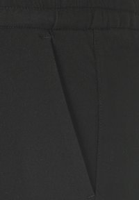 Zwarte broek gemaakt van geweven stof met een gladde textuur, met een vlakke voorkant en subtiele naaddetails. Elastische tailleband aan de bovenkant.