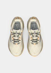 Pantofi sport bej deschis cu șireturi gri, partea superioară din plasă și accente galbene. Prezintă talpă texturată și branț moale.