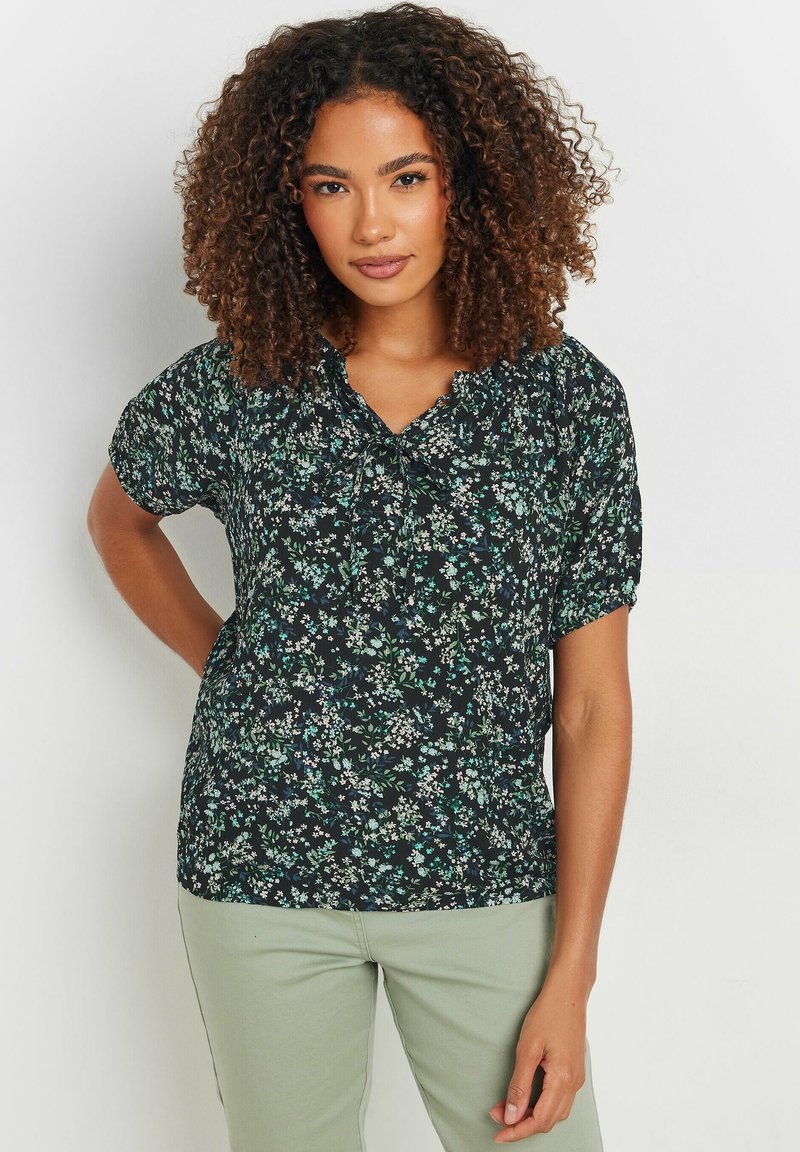 Blusa corta de manga corta negra con estampado floral en verde y blanco, con escote en V y corte relajado, hecha de tejido liviano.