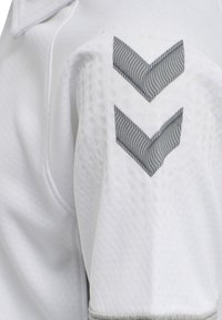 Witte sportshirt met textuurstof, gemêleerd met gaasdetails en grijze chevronpatronen op de mouwen.