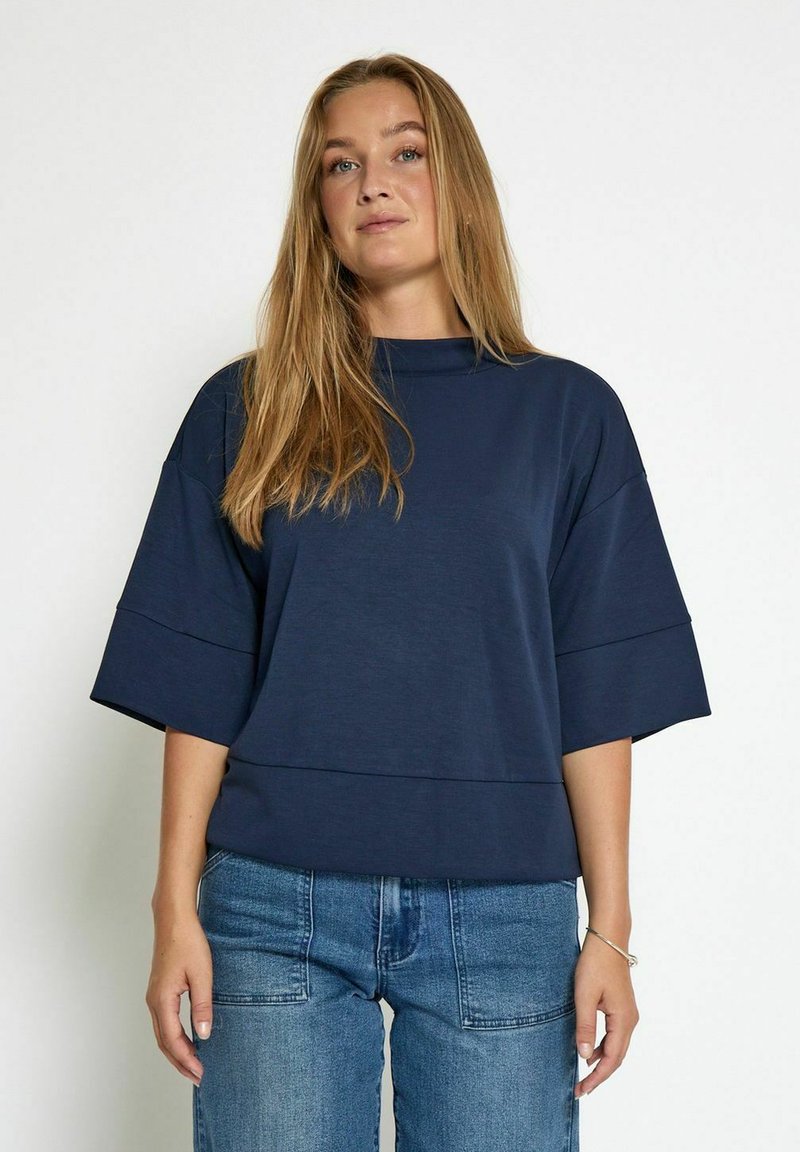 T-shirt surdimensionné bleu marine avec un col haut, de larges manches courtes et des rayures horizontales au niveau de la poitrine.