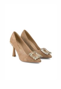 Beige suede high-heeled shoes with pointed toes, adorned with a rhinestone buckle on the front and a gold accent on the heel.