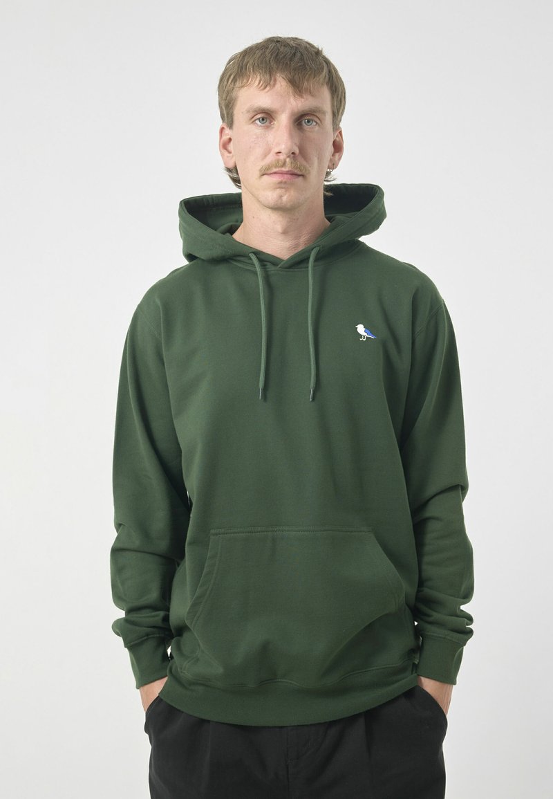 Green hoodie made of soft fabric, featuring a front pocket, adjustable drawstring hood, and a small blue and white bird logo on the chest.