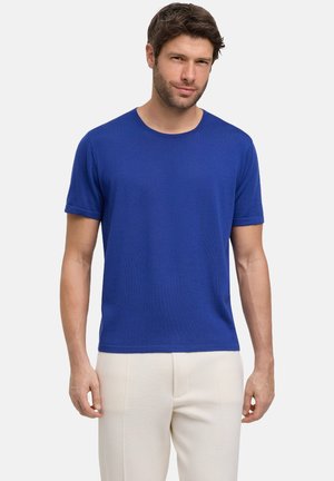 Maglietta a manica corta con collo rotondo in tessuto blu vibrante con un motivo testurizzato, abbinata a pantaloni di colore chiaro. Design semplice e moderno.