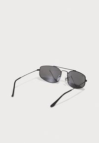 Ochelari de soare aviator negri cu lentile gri, cadru subțire din metal și suporturi de nas din silicon. Dispune de brațe elegante cu o textură netedă.