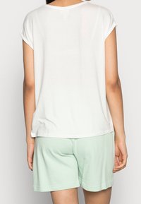 White, short-sleeve t-shirt with a relaxed fit, paired with light mint-green shorts, crafted from soft cotton fabric.