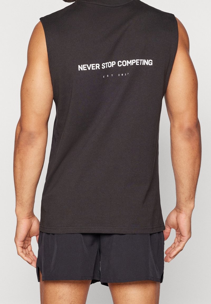 Chemise sans manches noire avec texte blanc "NEVER STOP COMPETING" et "EST 2017" au dos, en tissu léger.
