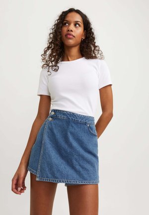 Denim wrap skirt featuring a side button closure, in a medium blue shade with a frayed hem and a smooth texture. Paired with a white t-shirt.