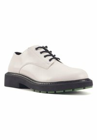 Scarpe stringate in pelle bianca con lacci neri, suola spessa nera e dettagli verdi sul battistrada. Tessuto liscio e design con punta arrotondata.