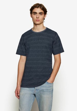 Dunkelblauses T-Shirt mit kurzen Ärmeln und einem strukturierten, gestreiften Muster. Rundhalsausschnitt, lockere Passform und weicher Stoff, kombiniert mit hellblauen Jeans.
