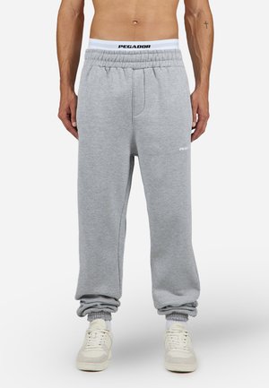 Gray sweatpants with an elastic waistband, featuring a white logo and cuffs. The fabric has a soft texture, suitable for casual wear.
