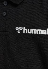 Svart pikétröja med ett texturerat tyg, två knappar och en vit logotyp med en bidesign och varumärkesnamnet "hummel" under.