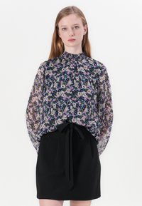 Blusa fluida e floreale con un collo alto, caratterizzata da un mix di piccoli fiori rosa, bianchi e blu su uno sfondo scuro, tessuto trasparente e polsi elasticizzati.