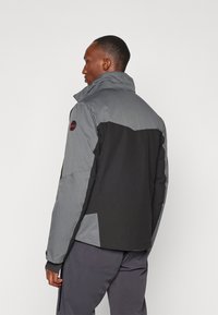 Chaqueta de hombre con un alto cuello, hecha de tela gris y negra. Diseño destacable de bloques de color y superficie texturizada. Puños ajustables incluidos.