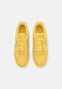 Gula Nike-sneakers med läderöverdel, perforerat tåparti, platta snören och vadderad sula. Stygnen detaljer och logotyp på tungan.