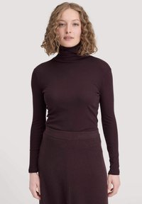 Bordeaux coltrui met lange mouwen, gemaakt van een zachte stof. Strak ontwerp, minimale textuur, gecombineerd met een bijpassende rok.