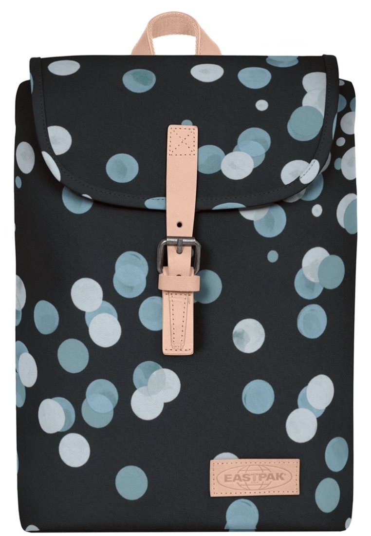 Ryggsäck med svart tyg med ett mönster av ljusblå och vita cirklar, ett beige läderrem och en rektangulär logotypapplikation.