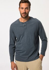Langärmliges, dunkelblaues Henley-Shirt mit rundem Ausschnitt und zwei Knöpfen; verfügt über einen weichen, strukturierten Stoff und genähte Säume.