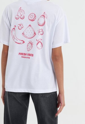T-shirt blanc avec des croquis de fruits rouges (banane, cerise, kiwi, poire, fraise, pastèque) et le texte "FRESH VIBES FRESH BITES" au dos.