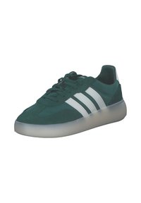 Zelené semišové tenisky s bílými třemi pruhy, kulatou špičkou, strukturovaným svrškem a průhlednou gumovou podrážkou. Šněrování ve stejné barvě.