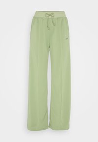 Světlé zelené tepláky s elastickým pasem, stahovací šňůrou, kapsami a malým černým logem na levé straně. Měkká tkanina, široké nohavice.