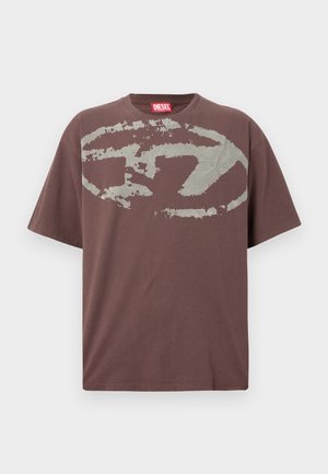 Καφέ κοντομάνικο μπλουζάκι με μεγάλο φθαρμένο γκρι ωοειδές γραφικό και ετικέτα μάρκας Diesel σε κόκκινο χρώμα μέσα στην κορώνα.