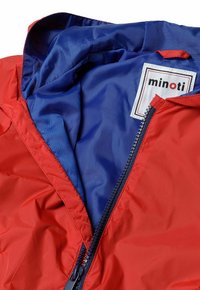 Jachetă roșie cu un căptușel albastru, având un fermoar frontal și o etichetă care afișează "minoti." Material exterior neted și lucios.