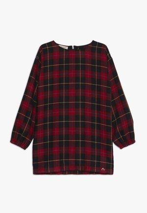 Rød og sort ternet top med lange ærmer, rund halsudskæring, indsnørede manchetter og gule detaljer; har lukning bagpå.