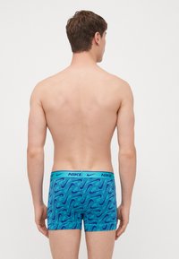 Blå boxershorts med ett vågmönster i varierande nyanser, med en kontrasterande Nike-logoband i turkos vid midjan.