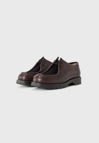 Scarpe in pelle marrone scuro con lacci, dotate di un pannello testurizzato nero nella parte superiore e suole nere spesse, su uno sfondo chiaro e semplice.