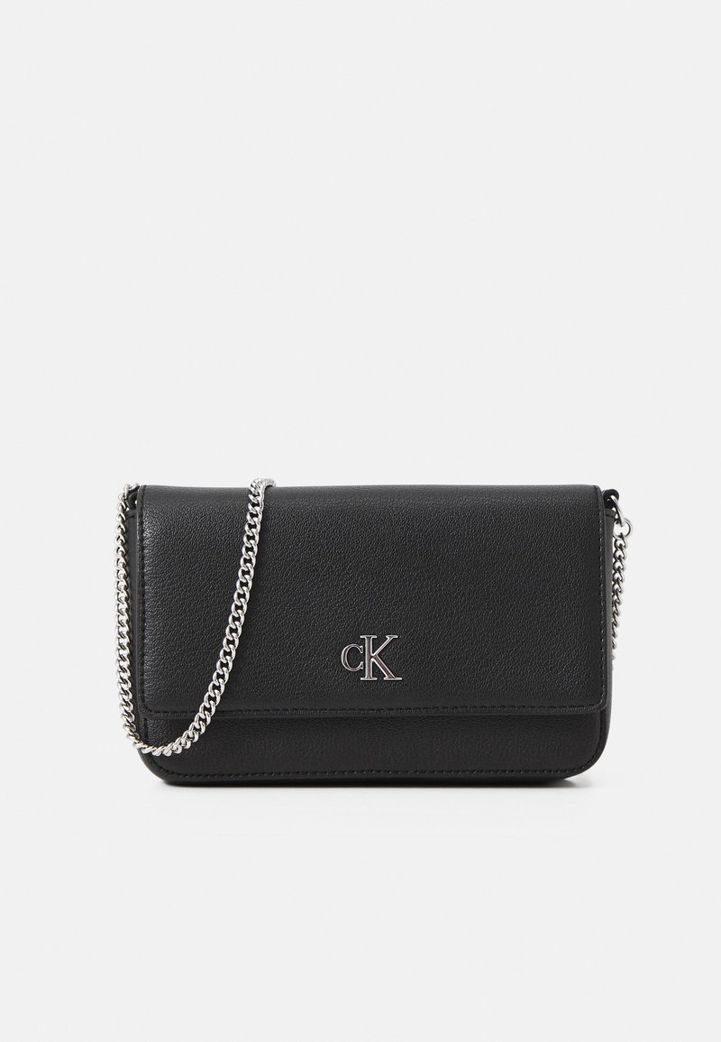 Črna usnjena torbica čez ramo z teksturiranim končnim obdelavo, srebrna verižica za nošenje, magnetno zapiranje na poklopcu in embosiran logotip na sprednji strani.