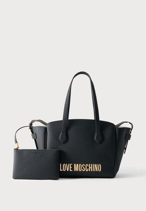 Black Love Moschino -käsilaukku ja sen kanssa sopiva pieni pussukka, molemmissa kullanväriset vetoketjut, yksinkertaisella vaalealla taustalla.