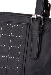 Zwarte handtas van textuurleer met een rasterpatroon van kleine metalen studs, met een ritsluiting en accenten van zilverkleurig beslag.
