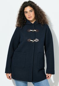 Tmavě modrý vlněný kabát s kapucí, vybavený zapínáním na kloubové uzávěry a dvěma náprsními kapsami, navržený v uvolněném střihu s texturovaným povrchem.