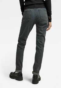 Jeans ajustados de color gris oscuro con una textura suave, que cuentan con cinco bolsillos y puños enrollados, combinados con zapatos de plataforma gruesos y negros.