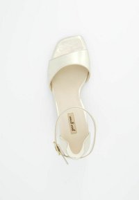 Sandal s otevřenou špičkou v metalické světlé béžové kůži, čtvercový design špice, tenký pásek s přezkou, polstrovaná stélka a značka na stélce.