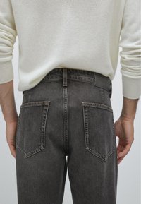 Ciemnoszare dżinsy typu slim fit. Posiadają dwie tylne kieszenie z ukośnym wykończeniem oraz skórzaną łatę w pasie.