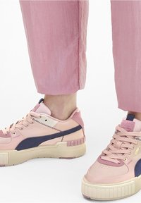 Jasnoróżowe sneakersy z połączeniem gładkich i teksturowanych materiałów, z granatowymi akcentami i masywną podeszwą. Zapięcie na sznurówki.