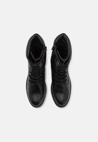 Botas de tobillo de cuero negro con un acabado suave, que presentan un diseño de cordones, un cuello acolchado y una cremallera exterior para un fácil acceso.