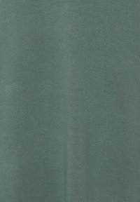 Tissu vert moyen doux avec une texture tricotée fine, présentant des plis subtils et des ombres.