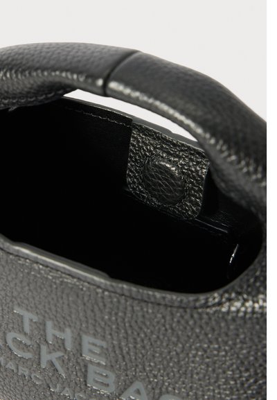 Zwarte gestructureerde leren tas met ronde handgreep en drukknopsluiting, met gedeeltelijk geopende binnenzijde.