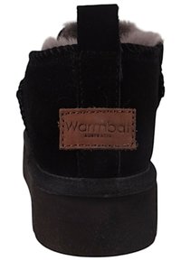 Czarne zamszowe botki do kostki z okrągłym noskiem, z brązową skórzaną metką z napisem "Warmbat Australia" i miękkim futerkiem w środku. Płaska, gumowa podeszwa.