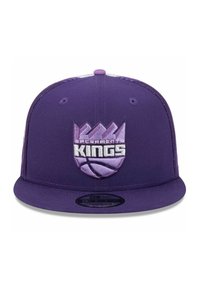 Purple snapback cap featuring an embroidered Sacramento Kings logo with a basketball and crown design. Flat brim with textured fabric.