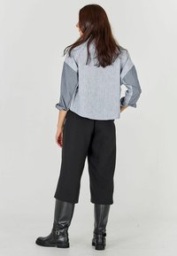 Gray and blue striped shirt with long sleeves, paired with black wide-leg pants and knee-high black boots. Smooth fabric with a relaxed fit.