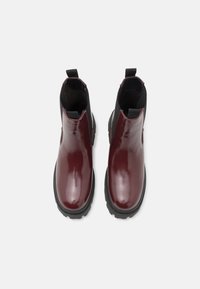 Bottines en cuir bordeaux avec des panneaux latéraux élastiques, bouts ronds et semelles en caoutchouc noir texturé. Tirants à l'arrière pour un enfilage facile.