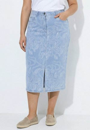 Lyseblå mellemlang denimnederdel med diskrete hvide blomsterprint, frontslids, lommer, båret med beige slip-on sko og hvid top.